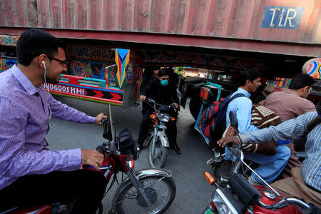 A motorcyclist slips through a gap in a barricade set up using shipping containers near the venue of a planned protest gathering organised by Awami Muslim League (AML), a political ally party of Imran Khan's Pakistan Tehreek-e-Insaf (PTI), in Rawalpindi, Pakistan, October 28, 2016. REUTERS/Faisal Mahmood