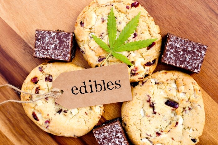 A cannabis leaf and a tag with the word edibles written on it that's been placed atop cookies and brownies.