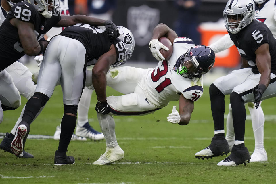 Houston Texans running back Dameon Pierce (31) is brought down by Las Vegas Raiders linebacker Denzel Perryman and others during the first half of an NFL football game Sunday, Oct. 23, 2022, in Las Vegas. (AP Photo/John Locher)