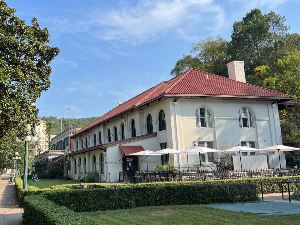 A historic, Spanish-style building with chairs and tables with umbrellas outside.