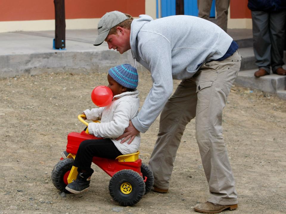 Prince Harry plays with a boy on a tricycle
