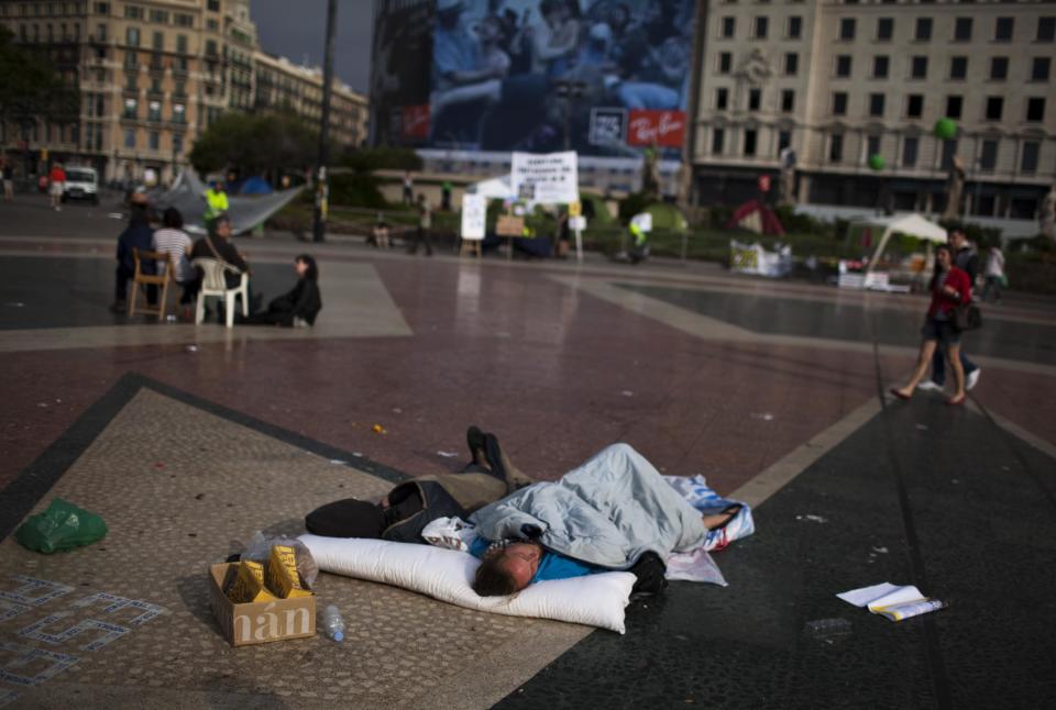A man sleeps on the ground as he spent the night at the Catalunya square during a protest to mark the anniversary of the "Indignados" movement in Barcelona, Spain, Sunday May 13, 2012. Spaniards angered by increasingly grim economic prospects and unemployment hitting one out of every four citizens protested in droves Saturday in the nation's largest cities, marking the one-year anniversary of a spontaneous movement that inspired similar anti-authority demonstrations across the planet. (AP Photo/Emilio Morenatti)