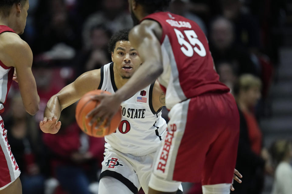 San Diego State guard Matt Bradley, center, defends as UNLV guard EJ Harkless , right, dribbles during the first half of an NCAA college basketball game Saturday, Feb. 11, 2023, in San Diego. (AP Photo/Gregory Bull)