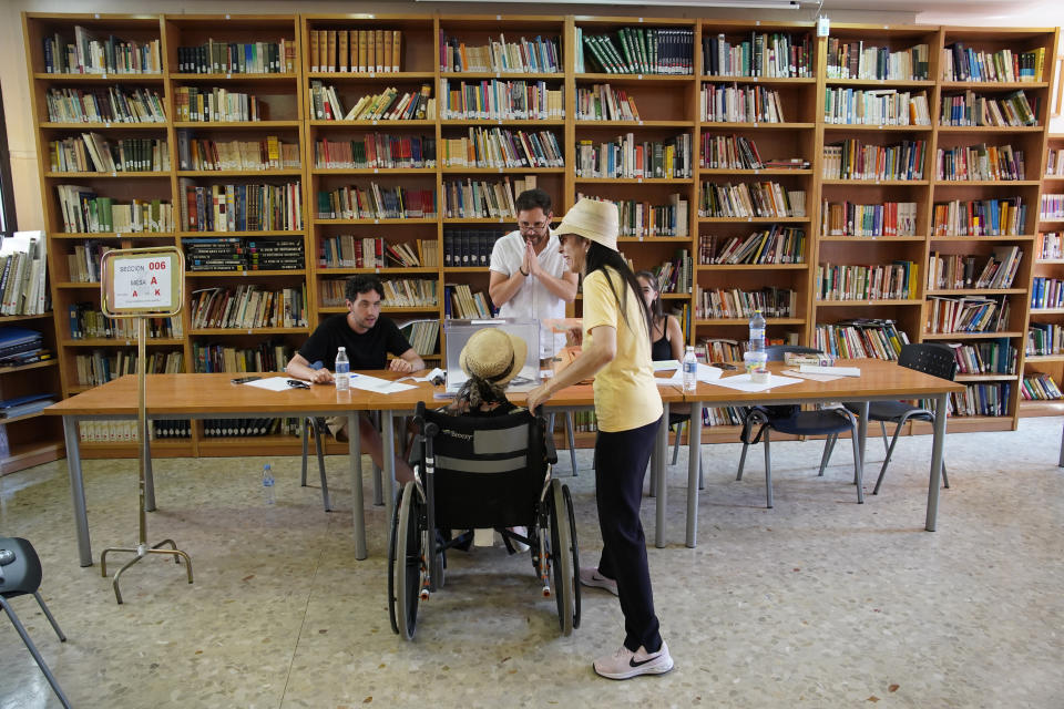 An election worker, center, gestures to a voter on a wheelchair at a polling station for Spain's general election, in Madrid, Sunday, July 23, 2023. Sunday's election could make the country the latest European Union member to swing to the populist right, a shift that would represent a major upheaval after five years under a left-wing government. (AP Photo/Andrea Comas)