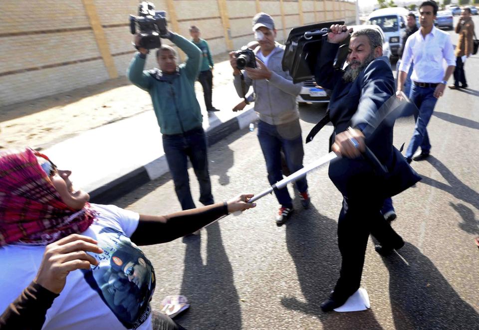 A supporter of the head of Egypt's military, Abdel-Fattah el-Sissi, left, wearing a t-shirt with his image, scuffles with a Muslim Brotherhood lawyer, Ahmed Kamel, after she struck him outside a makeshift courtroom at the national police academy, in an eastern suburb of Cairo, Egypt, Saturday, Feb. 1, 2014. The trial of Egypt's ousted president, Mohammed Morsi and 14 others also accused of inciting the killing of protesters resumed on Saturday. The trial is one of four Morsi and top leaders of his Muslim Brotherhood face with the charges levelled against them mostly carrying the death penalty. (AP Photo/Ahmed Omar)