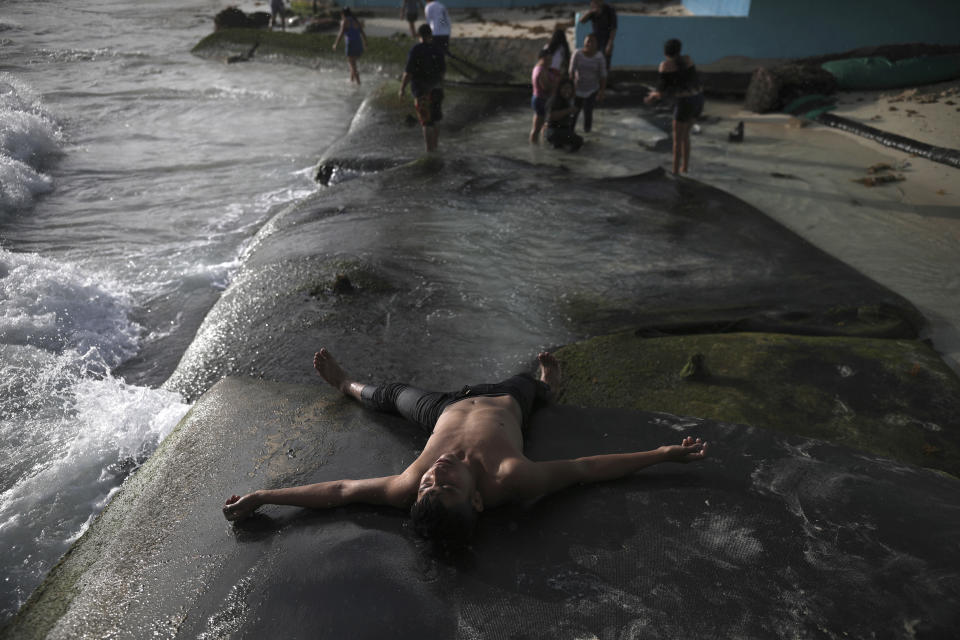 A bather lies spread-eagle on the shore of Mamitas beach, in Playa del Carmen, Quintana Roo state, Mexico, Friday, Jan. 1, 2021. Concern is spreading that the winter holiday bump in tourism could be fleeting because it came as COVID-19 infections in both Mexico and the United States were reaching new heights. (AP Photo/Emilio Espejel)