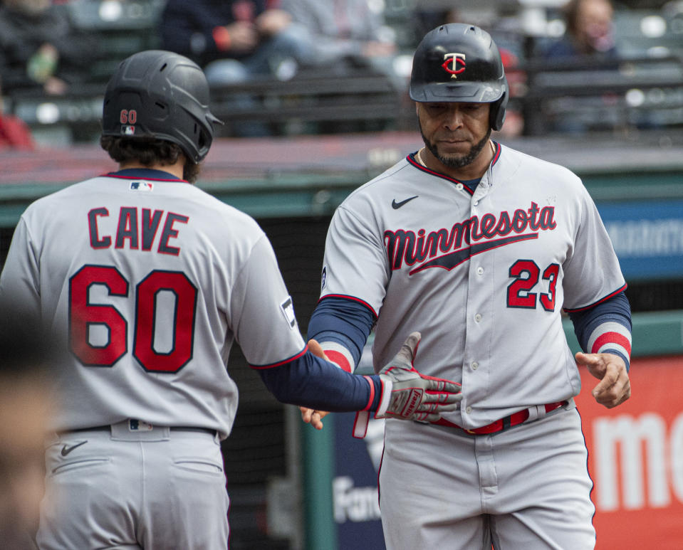 Minnesota Twins' Nelson Cruz is greeted by teammate Jake Cave after scorning on a sacrifice fly by Jorge Polanco during the fourth inning of a baseball game against the Cleveland Indians in Cleveland, Monday, April 26, 2021. (AP Photo/Phil Long)