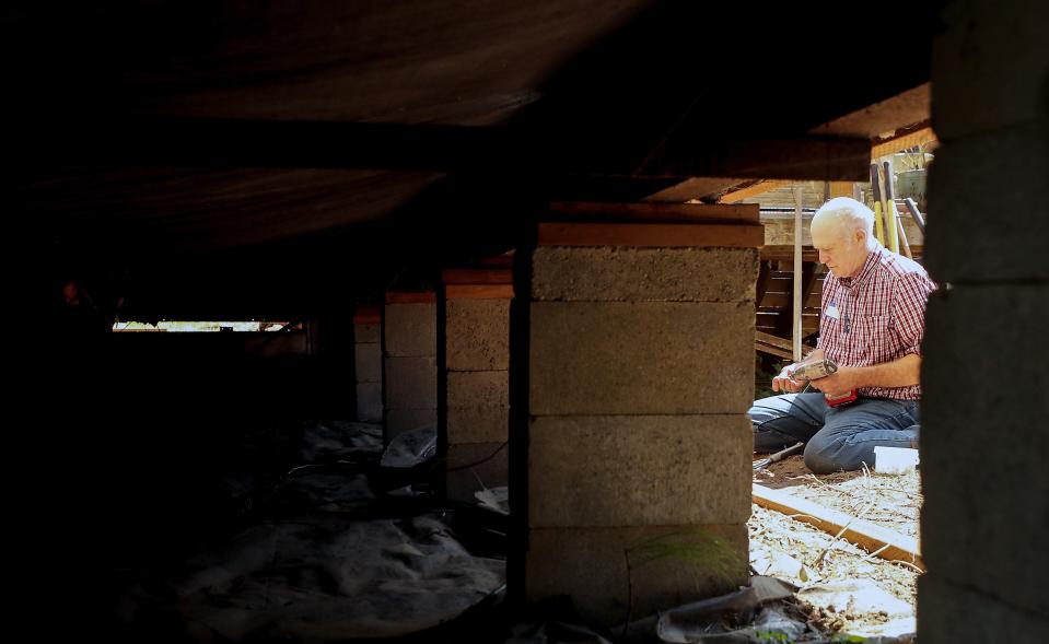 Volunteer Ryan Amberfield, of Bainbridge Island, is framed by the supports of a mobile home as he works on replacing the skirting of the home at Poulsbo Mobile Home Park on Thursday, July 27, 2023.