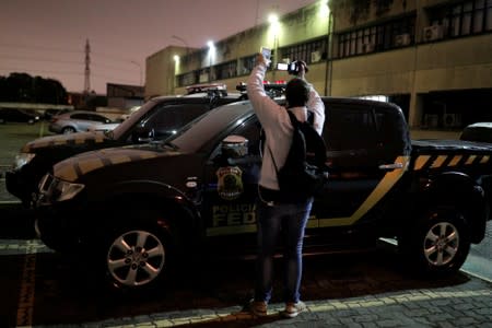 FILE PHOTO: A cameraman records pickup trucks with livery resembling Brazil's federal police which were used during the theft at Guarulhos airport in Sao Paulo