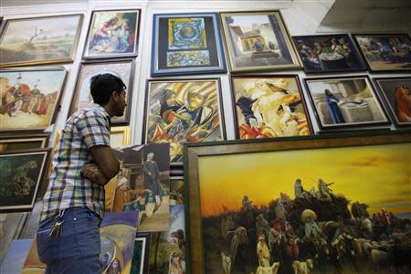 A customer looks at paintings at a gallery in Baghdad's Karrada district, September 18, 2013. REUTERS/ Thaier Al-Sudani