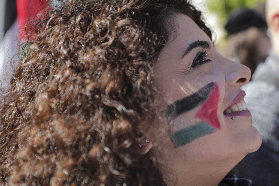 A protester with her face painted with the colors of the Palestinian national flag smiles during a protest is held against the proposed peace deal for the Middle East by President Donald Trump, near the U.S. embassy in Aukar, east of Beirut, Lebanon, Sunday, Feb. 2, 2020. Hundreds of Lebanese and Palestinians demonstrated Sunday near the U.S. embassy in Lebanon in rejection to a White House plan for ending the Israeli-Palestinian conflict. (AP Photo/Hassan Ammar)