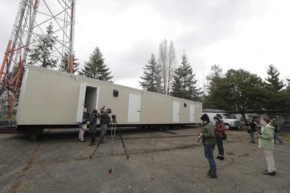 Reporters and photographers work Tuesday, March 3, 2020, at the site in South Seattle where King County will be placing several temporary housing units like the one shown here to house patients undergoing treatment and isolation in response to the COVID-19 coronavirus. (AP Photo/Ted S. Warren)