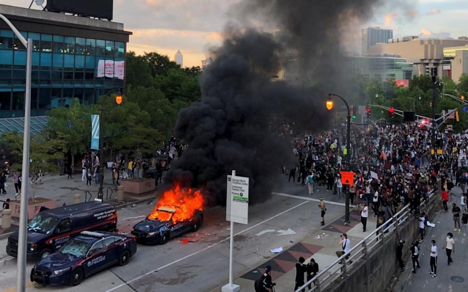 An Atlanta Police car burns as people protest against the death in Minneapolis police custody of African-American man George Floyd - Reuters