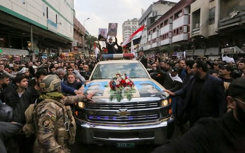 Mourners surround a car carrying the coffin of Iranian military commander Qasem Soleimani - Credit: &nbsp;SABAH ARAR/AFP via Getty Images