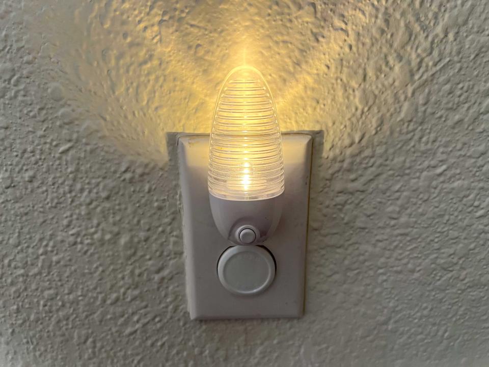 A nightlight turned on and plugged into a wall