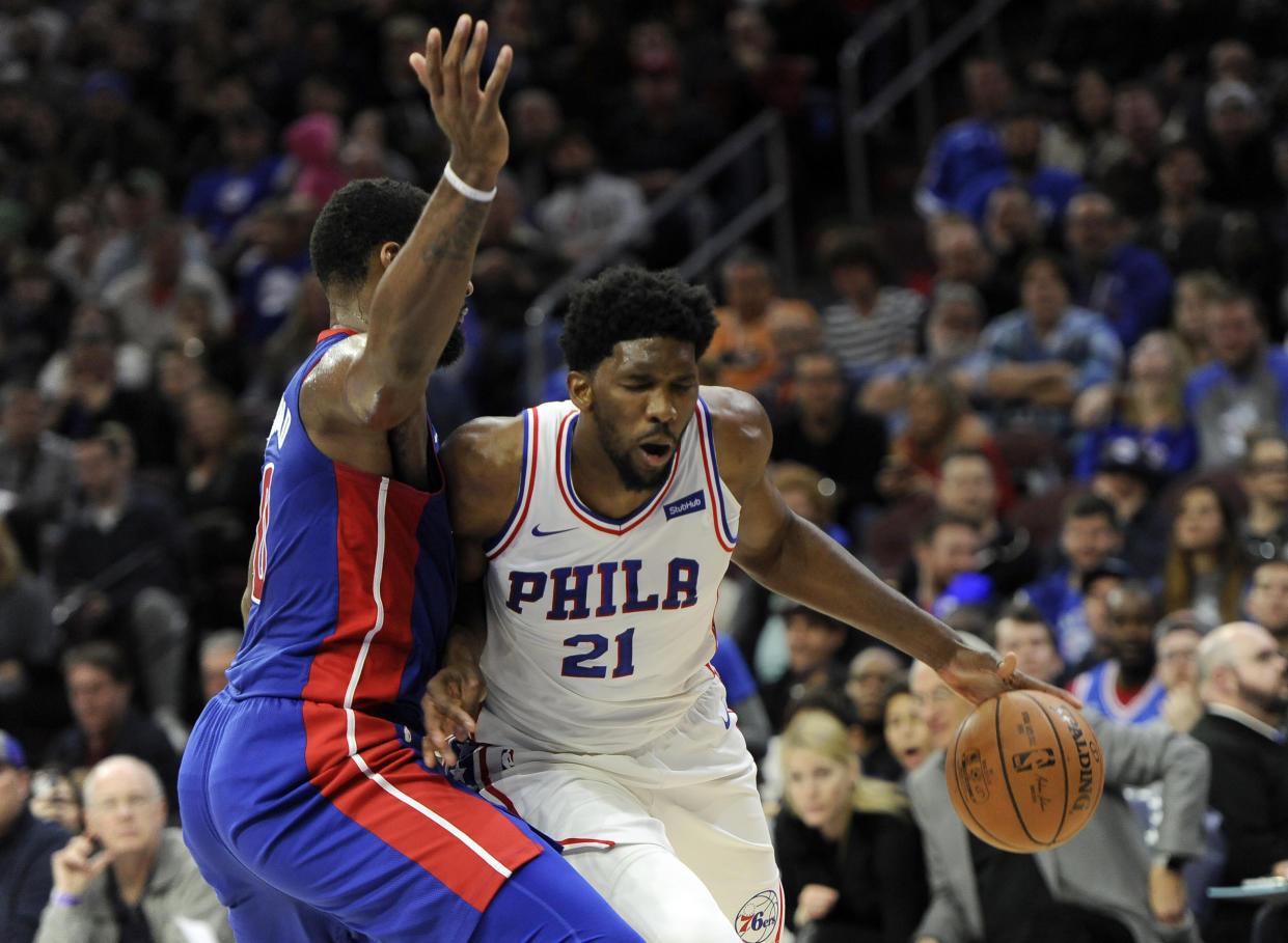 Joel Embiid (21) drives to the basket past Andre Drummond. (AP)