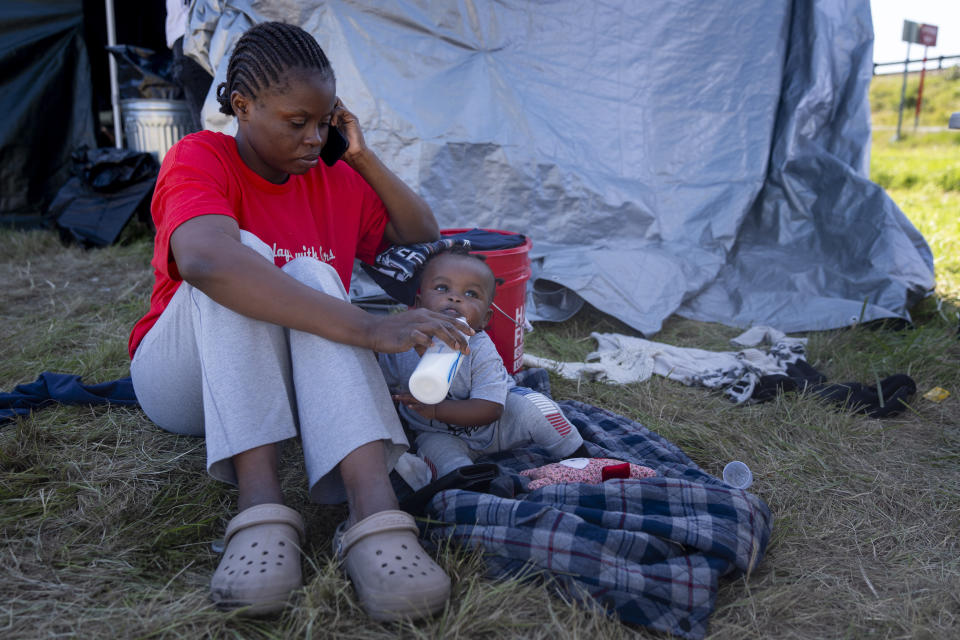 Prisilia Mayingila gives a bottle to seven month-old daughter Victoria Manunga at an encampment of asylum-seekers mostly from Venezuela, Congo and Angola next to an unused motel owned by the county, Wednesday, June 5, 2024, in Kent, Washington. The group of about 240 asylum-seekers is asking to use the motel as temporary housing while they look for jobs and longer-term accommodations. (AP Photo/Lindsey Wasson)