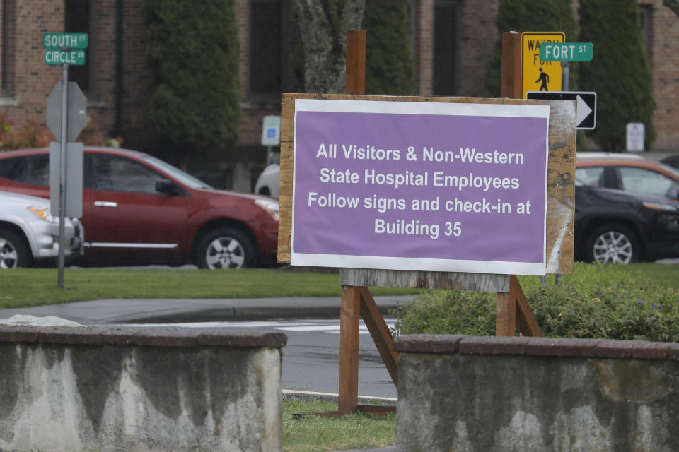 In this April 22, 2020, photo, a sign at Western State Hospital in Lakewood, Wash., directs visitors and non-hospital employees to check in at another building where health screening is done. Employees at the facility — the state's largest psychiatric hospital — say that problems with testing for the coronavirus likely produced inaccurate results and exposed them to the virus a second time. (AP Photo/Ted S. Warren)