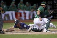 Seattle Mariners' Jake Bauers slides home safe on a throwing error by Paul Blackburn as Oakland Athletics' Yan Gomes applies the tag during the second inning of a baseball game in Oakland, Calif., Tuesday, Sept. 21, 2021. (AP Photo/Jed Jacobsohn)