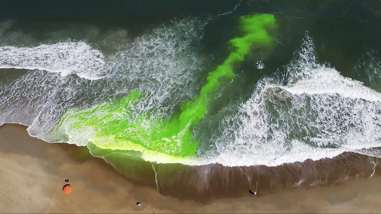 Beachfront from above shows green dye in water.