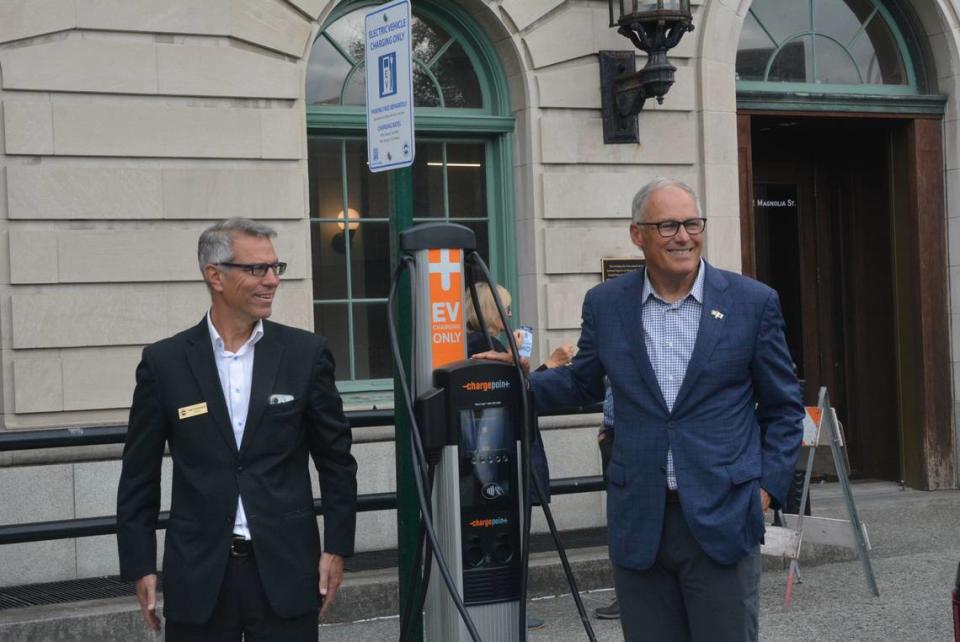 Bellingham Mayor Seth Fleetwood, left, shows Washington state Gov. Jay Inslee a public electric vehicle charging station on Tuesday, Sept. 12, 2023, in Bellingham, Wash. Inslee was visiting Whatcom County to see several local renewable energy projects that were funded through the Climate Commitment Act and other sources.