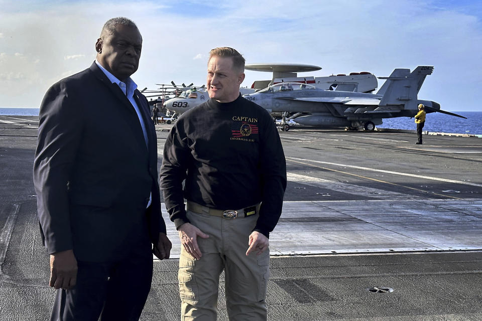 Defense Secretary Lloyd Austin, left, talks with the commanding officer of the USS Gerald R. Ford, Navy Capt. Rick Burgess, during an unannounced visit to the ship on Wednesday, Dec. 20, 2023. The USS Gerald R. Ford has been sailing just a few hundred miles off the coast of Israel to prevent the Israel-Hamas war from expanding into a regional conflict. (AP Photo/Tara Copp)