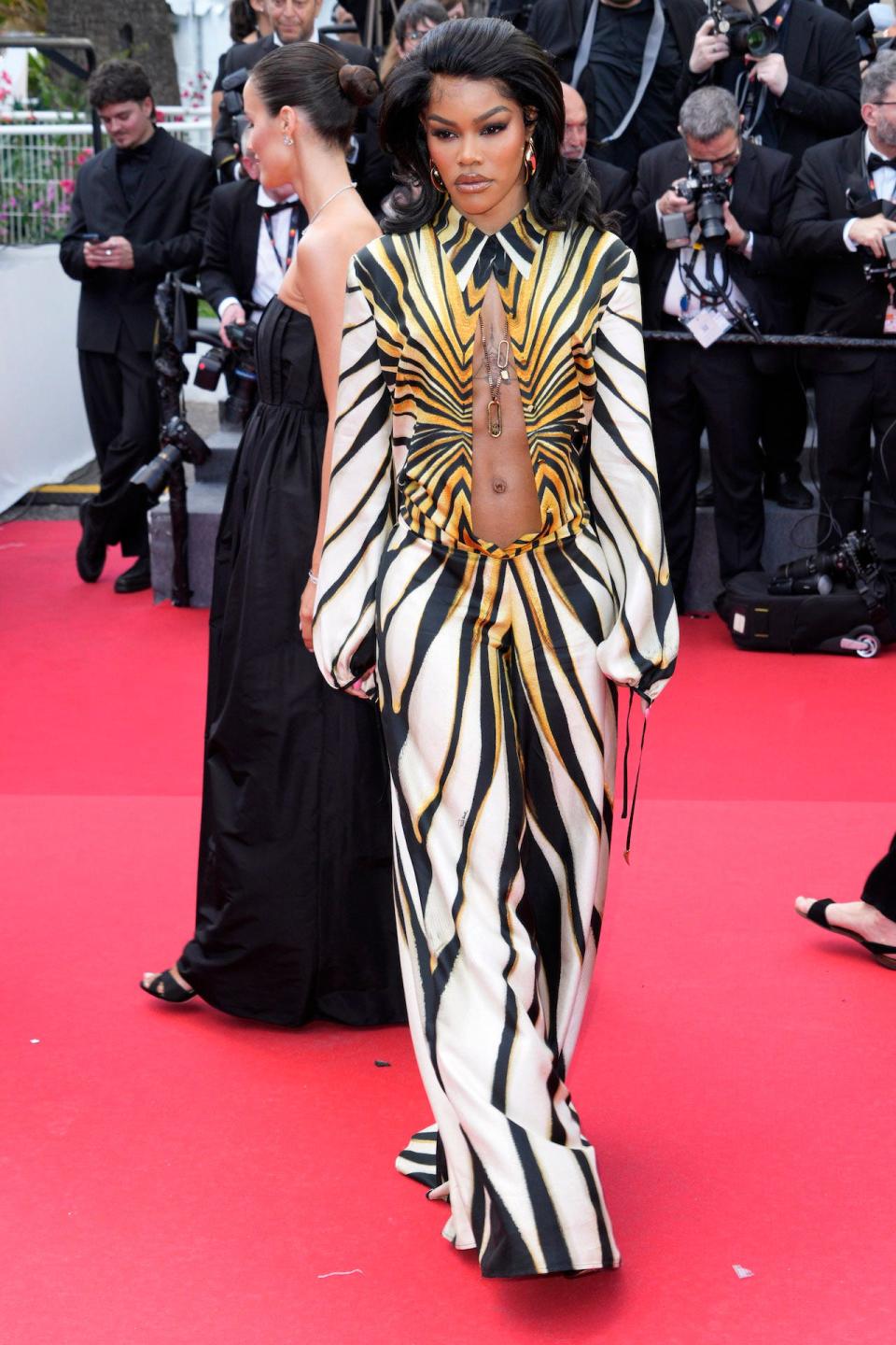 Actor Teyana Taylor wearing a black, white, and yellow jumpsuit with a cutout on the red carpet.