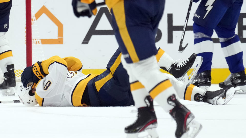 Nashville Predators center Cody Glass (8) goes down after getting hit in the head by a shot during the second period of an NHL hockey game against the Tampa Bay Lightning Tuesday, Oct. 10, 2023, in Tampa, Fla. (AP Photo/Chris O'Meara)