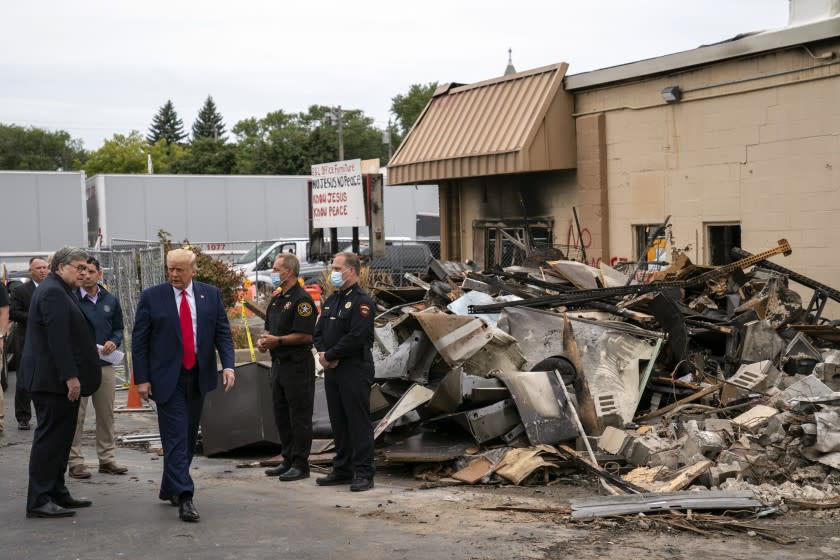 President Donald Trump tours an area Tuesday, Sept. 1, 2020, that was damaged during demonstrations after a police officer shot Jacob Blake in Kenosha, Wis. At left is Attorney General William Barr and acting Homeland Security Secretary Chad Wolf. (AP Photo/Evan Vucci)