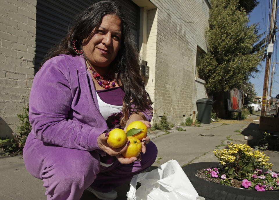 Needa Bee, who lives in a camper in Oakland with her teenage daughter, holds lemons, Thursday, April 2, 2020, in Oakland, Calif. Bee is the founder of a grassroots collective that administers to roughly 40 Oakland homeless encampments. They've been asking for donations of lemons and vinegar to sanitize hands since bleach and Lysol are so hard to get, distributing raw garlic for an immune boost, and collecting aloe plants to make hand sanitizer. (AP Photo/Ben Margot)