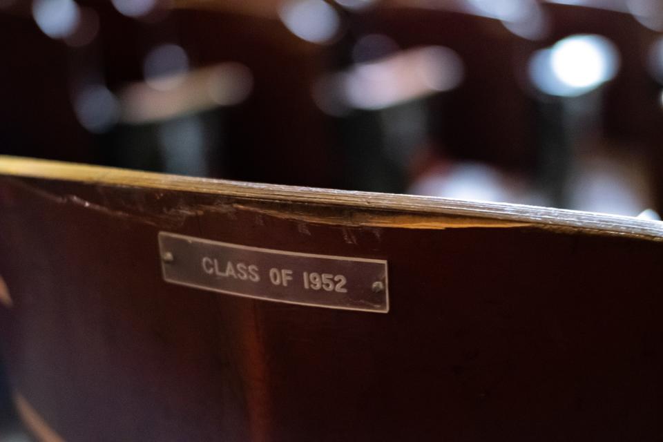 A worn plaque reading Class of 1952 adorns the tattered back of an auditorium seat at The Strand.