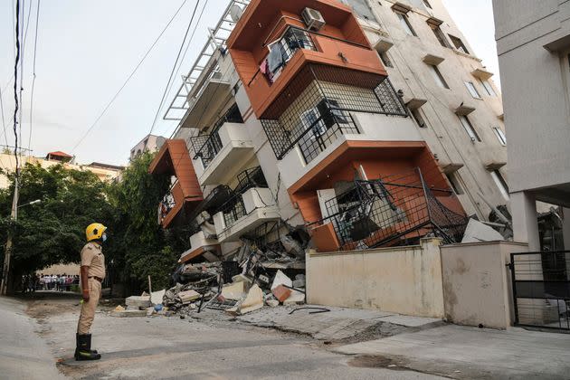 An emergency responder watches a multistory apartment building that collapsed without any reported casualties in Bangalore, India, on Oct. 7. (Photo: MANJUNATH KIRAN/AFP via Getty Images)