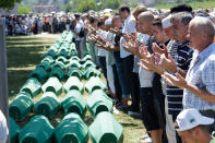 <p>Bosnian Muslim people pray in front of coffins during a funeral ceremony for dozens of newly identified victims of the 1995 massacre, at the memorial centre of Potocari near Srebrenica, 150 kms north east of Sarajevo, Bosnia, Tuesday, July 11, 2017. (Photo: Amel Emric/AP) </p>