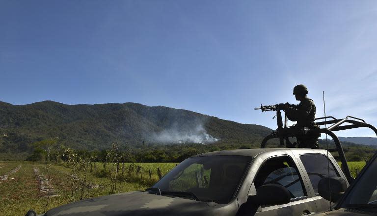 A soldier observes as smoke rises from a military helicopter that was shot down in Villa Purificacion, Jalisco State, Mexico on May 2, 2015