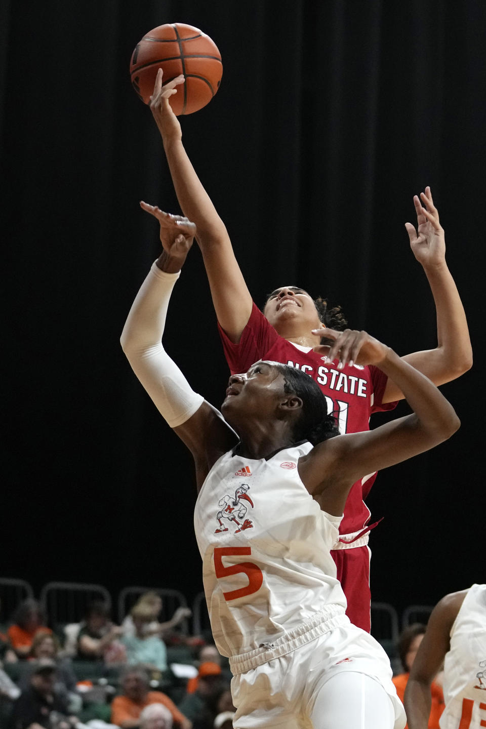 North Carolina State guard Madison Hayes, top, shoots as Miami guard Jaida Patrick (5) defends during the first half of an NCAA college basketball game Thursday, Jan. 18, 2024, in Coral Gables, Fla. (AP Photo/Lynne Sladky)