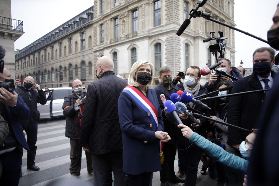 FILE - In this May 1, 2021, file photo, French far-right leader Marine le Pen, center, talks to media after laying a wreath during a ceremony in Paris. Bubbling beneath France’s political landscape is an assortment of ultra-right groups, a subculture that shot to the nation’s attention when a young man slapped President Emmanuel Macron and blurted out a centuries-old royalist cry. Le Pen was among political chiefs to quickly condemn the assault. (AP Photo/Thibault Camus, File)