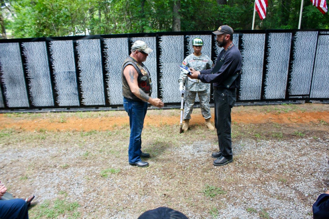 Opening ceremony held in 2016 for the Vietnam Moving Memorial Wall at the Trail of Honor. Duane 'Sarge' Dabore starts his salute before accepting the ceremonial flag from David 'Stupid' McElroy.