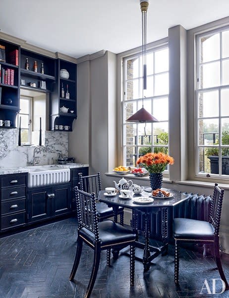 Black cabinetry complements the dark chevron floors and vintage bobbin chairs in the kitchen of fashion designer Roubi L’Roubi and Belgian financier Pierre Lagrange’s <a rel="nofollow noopener" href="https://www.architecturaldigest.com/story/veere-grenney-designed-roubi-l-roubi-london-townhouse-article?mbid=synd_yahoo_rss" target="_blank" data-ylk="slk:London penthouse;elm:context_link;itc:0;sec:content-canvas" class="link ">London penthouse</a>, which was designed by Veere Grenney.