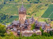 Auf einem Berg thront die Burganlage Cochem über der gleichnamigen rheinland-pfälzischen Stadt an der Mosel. Als Zollburg wurde der Bau wohl bereits um 1100 errichtet. Im 17. Jahrhundert wurde die mittelalterliche Gipfel- oder Höhenburg wurde jedoch zerstört und etwa hundert Jahre später im Stil der Burgenromantik neugotisch wieder neu errichtet. (Bild: iStock / ElenaKlippert)