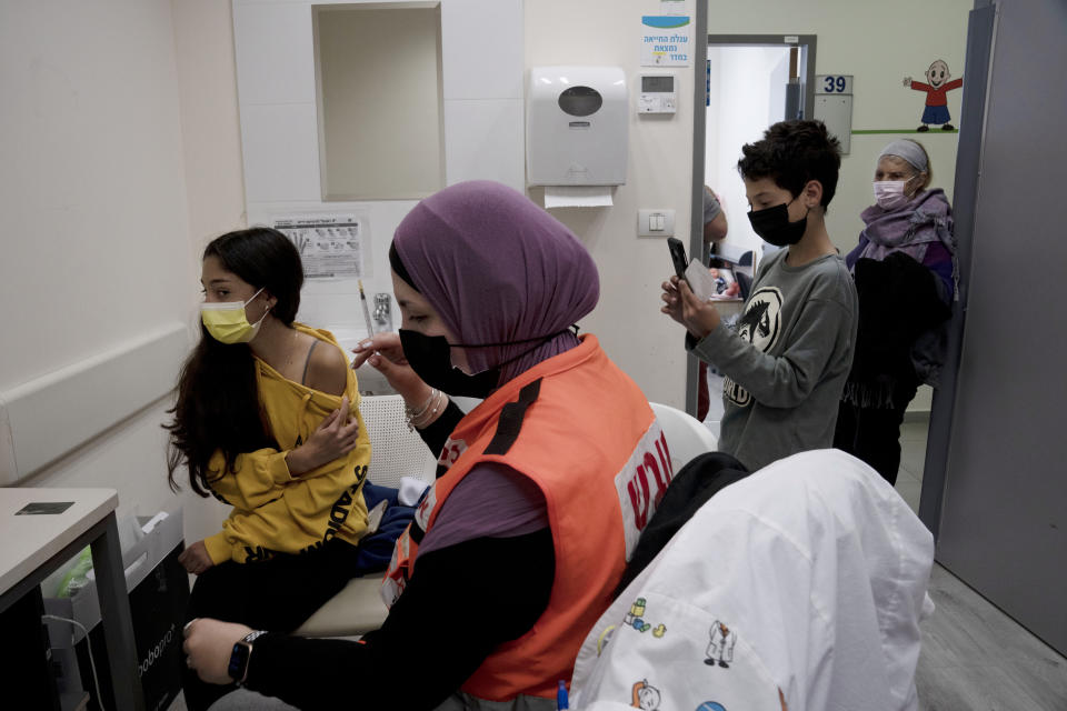 N'amah Yetzhak Abohaikal, a volunteer with the women's unit of United Hatzalah emergency service, prepares administer the COVID-19 vaccine to a teen girl as her brother and grandmother watch, at Clalit Health Services in Mevaseret Zion, Tuesday, Jan. 11, 2022. (AP Photo/Maya Alleruzzo)