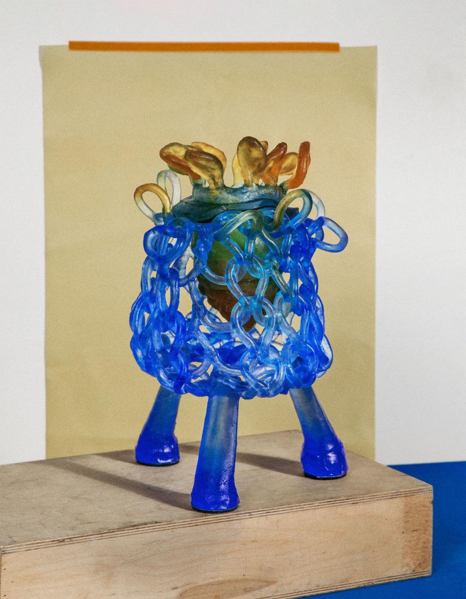 abstract blue glass loopy vase on raised feet with brownish tendrils that look like flowers