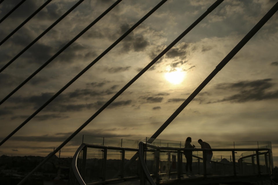 People stand on Halic Bridge over Golden Horn, in Istanbul, Friday, May 28, 2021, hours before the start of a weekend curfew. (AP Photo/Emrah Gurel)