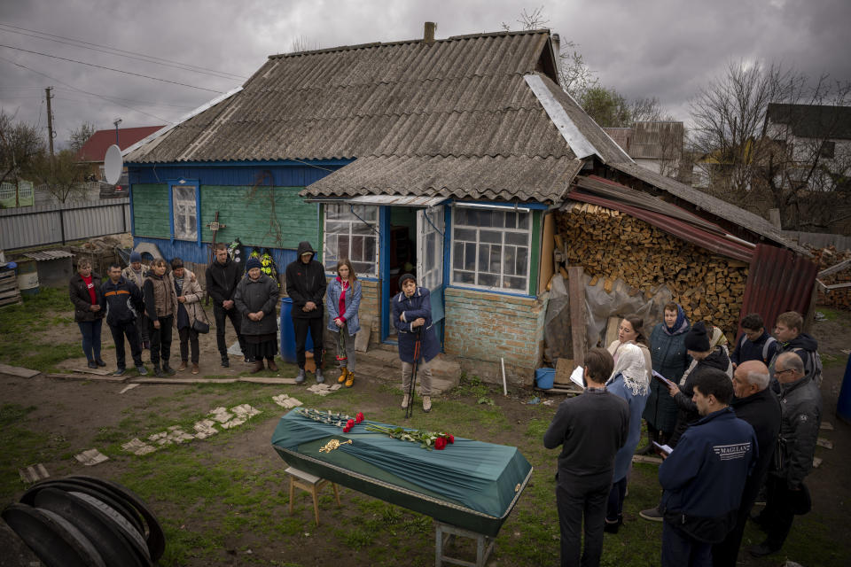 Friends and neighbors of Mykola "Kolia" Moroz, 47, gather during a funeral service at his home in the Ukrainian village of Ozera, near Bucha, on Tuesday, April 26, 2022. Russian soldiers took Kolia from his house on March 15. He was tortured and shot, his body found two weeks later in a village 15 kilometers (9 miles) away where Russians set up a major forward operating base for their assault on the capitol, Kyiv. (AP Photo/Emilio Morenatti)