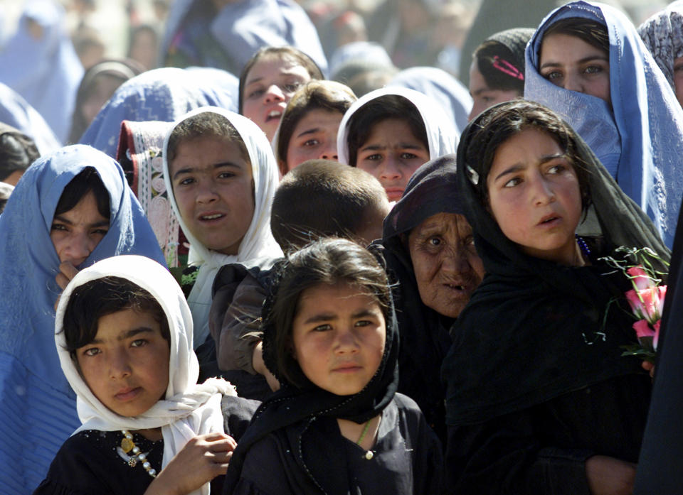 Afghan women and girls watch the arrival of Afghan President Hamid Karzai in Afghanistan's central Ghor province, July 26, 2003. The US-backed president, who spent half a day in Ghor together with cabinet ministers and met with leaders provincial to promise after the war reconstruction aid, keen to show that its influence is expanding beyond Kabul to often unruly outlying provinces.  REUTERS/Ahmad Masood RD/DB