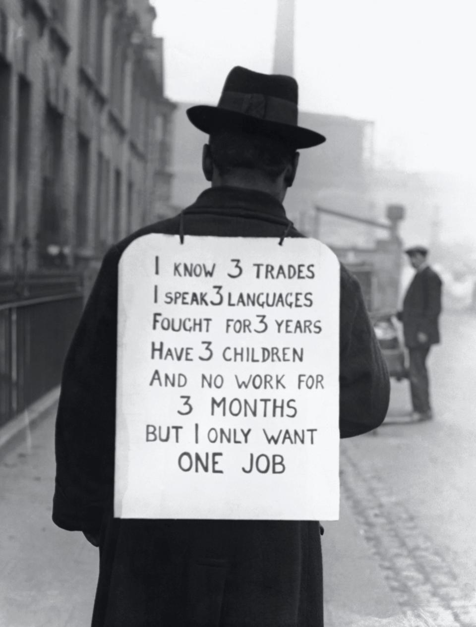 man wears sign that reads: "I know 3 trades speak 3 languages fought for 3 years have 3 children and no work for 3 months but i only want 1 job"