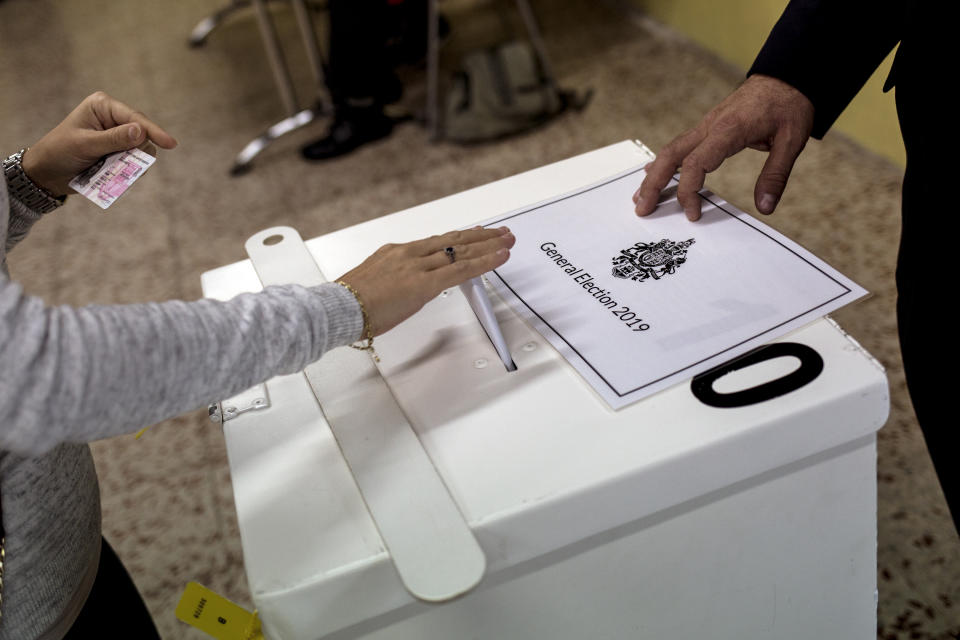 A woman places her vote during general elections in Gibraltar, Thursday Oct. 17, 2019. An election for Gibraltar's 17-seat parliament is taking place Thursday under a cloud of uncertainty about what Brexit will bring for this British territory on Spain's southern tip.(AP Photo/Javier Fergo)