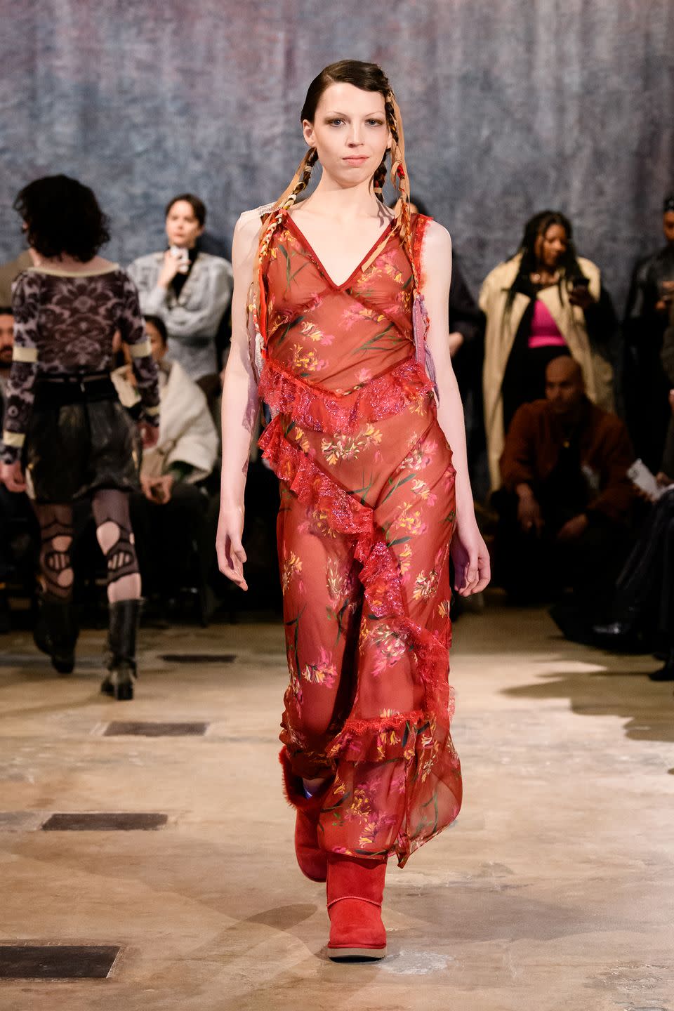 a model walks the runway in a transparent red dress