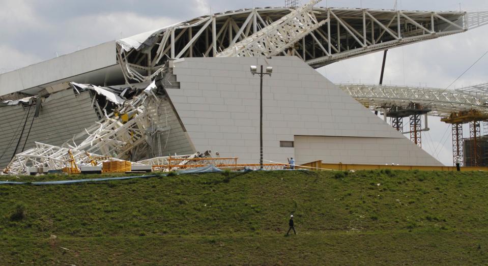 Workers stand near a crane that collapsed on the site of the Arena Sao Paulo stadium, known as "Itaquerao", which will host the opening soccer match of the 2014 World Cup, in Sao Paulo