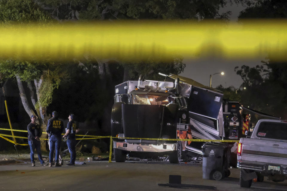 FILE - In this June 30, 2021 file photo ATF investigators stand next to the remains of an armored Los Angeles Police Department tractor-trailer after illegal fireworks seized at a home exploded in the containment chamber, in South Los Angeles. Arturo Ceja III, the man who stockpiled illegal fireworks in his South Los Angeles backyard, which were later improperly detonated by police, likely causing a massive blast in late June that rocked a neighborhood and injured 17 people, now faces a decade in federal prison. Ceja pleaded guilty Monday, Aug. 30 to one count of transportation of explosives without a license.(AP Photo/Ringo H.W. Chiu, File)