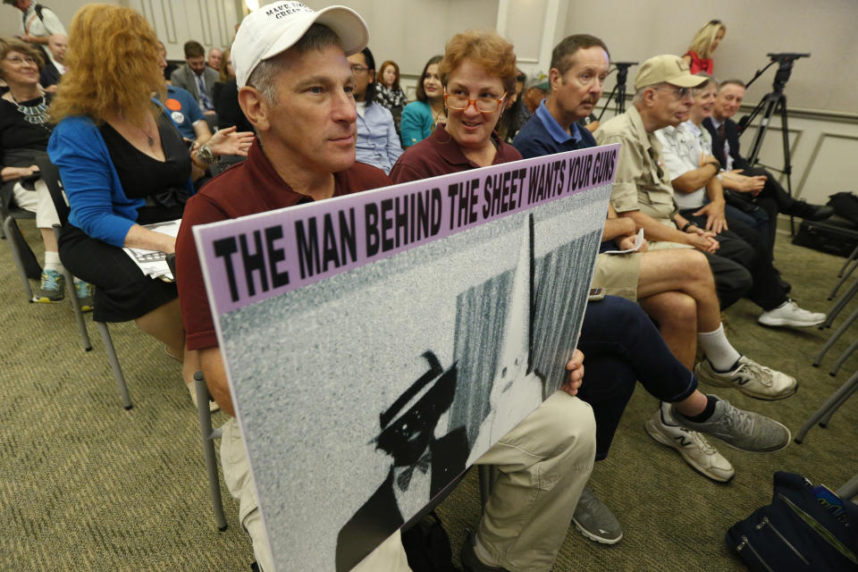 Ed Gomez, of Fairfax, Va., holds a sign depicting a photo that was on Gov. Northam's facebook page as he attends the second day of a Virginia Crime Commission meeting on gun issues at the Capitol in Richmond, Va., Tuesday, Aug. 20, 2019. Democratic Gov. Ralph Northam called the special session after a city employee opened fire in a Virginia Beach municipal complex May 31. (AP Photo/Steve Helber)